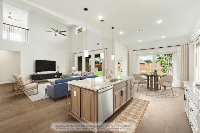 kitchen featuring light wood finished floors, visible vents, a sink, light stone countertops, and stainless steel dishwasher