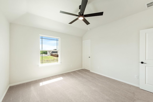 empty room featuring light carpet, lofted ceiling, visible vents, and baseboards