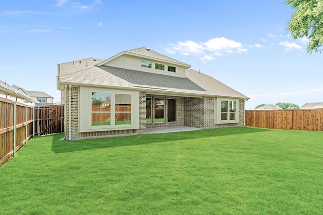 back of property with roof with shingles, a lawn, a fenced backyard, and brick siding