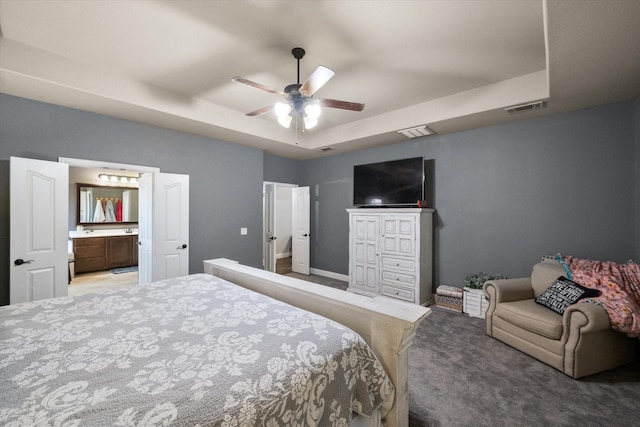 carpeted bedroom with ceiling fan, connected bathroom, and a tray ceiling