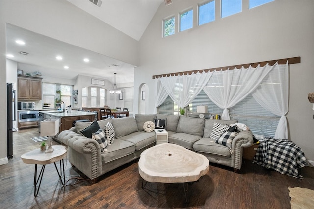 living room with dark hardwood / wood-style floors, high vaulted ceiling, and plenty of natural light