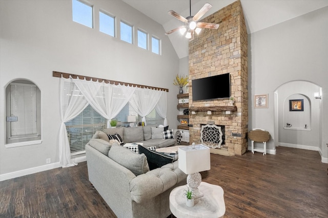 living room with dark hardwood / wood-style floors, high vaulted ceiling, ceiling fan, and a stone fireplace