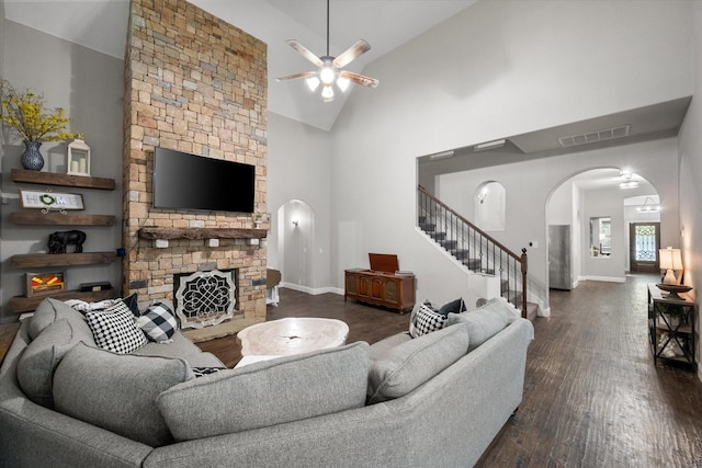 living room with dark hardwood / wood-style floors, ceiling fan, a fireplace, and high vaulted ceiling