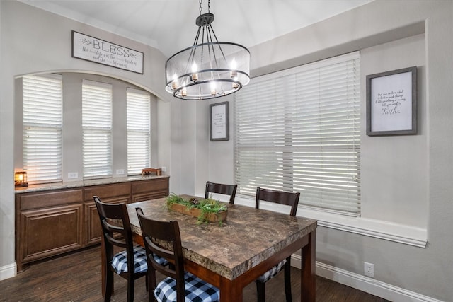 dining area featuring dark wood-type flooring and an inviting chandelier