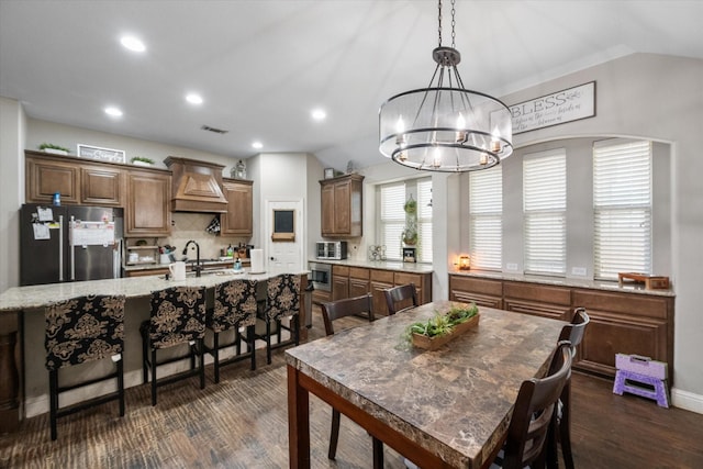 dining area with dark hardwood / wood-style flooring, a chandelier, lofted ceiling, and sink