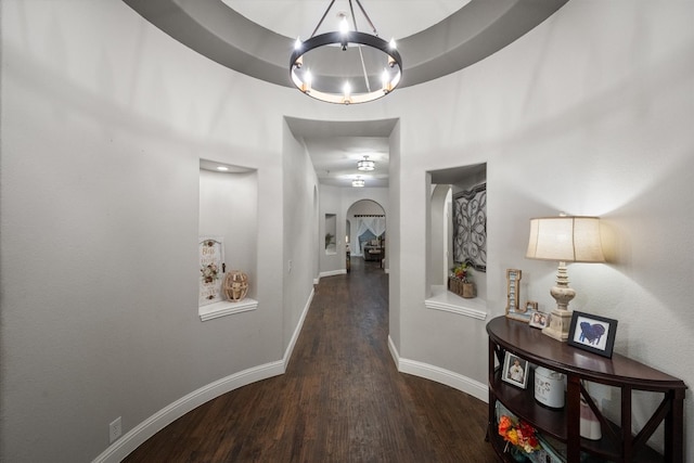 hall with dark wood-type flooring and a chandelier