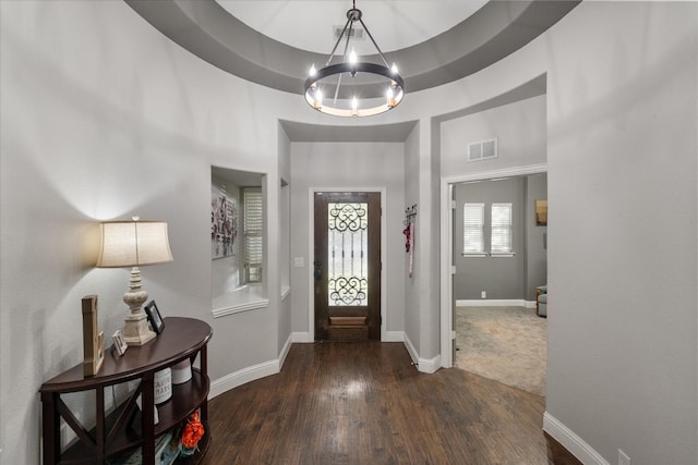 entrance foyer featuring a towering ceiling, dark wood-type flooring, and a notable chandelier