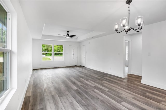 empty room featuring dark wood-type flooring, a raised ceiling, and ceiling fan with notable chandelier