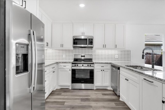 kitchen featuring white cabinetry, sink, light stone counters, and stainless steel appliances