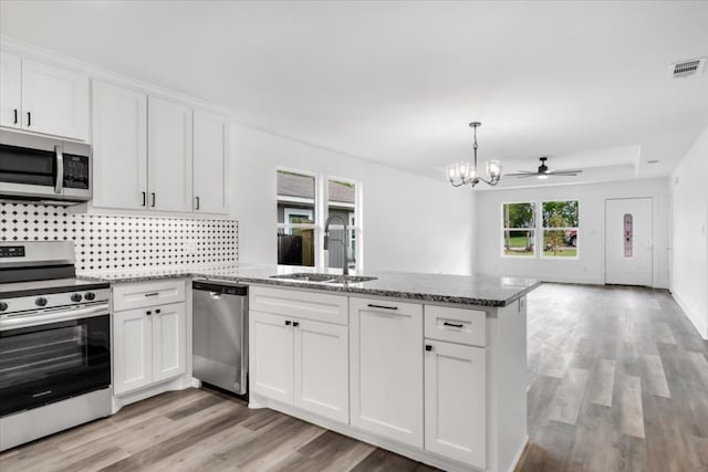 kitchen featuring white cabinets, dark stone counters, light wood-type flooring, and stainless steel appliances