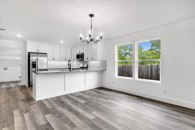 kitchen featuring an inviting chandelier, stainless steel appliances, white cabinetry, and light hardwood / wood-style floors