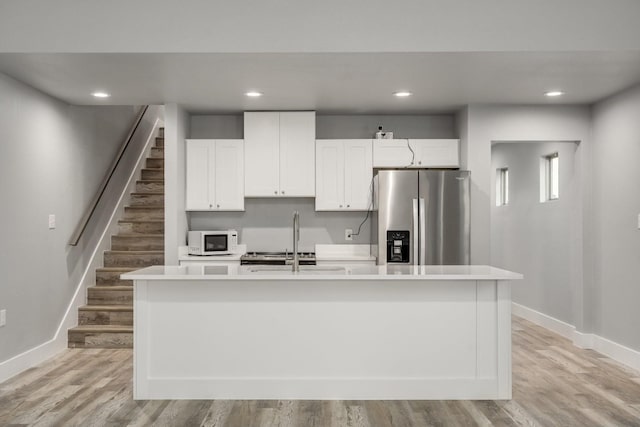 kitchen featuring light hardwood / wood-style flooring, an island with sink, and stainless steel fridge with ice dispenser