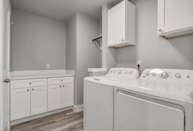 laundry room featuring cabinets, light wood-type flooring, and washing machine and dryer