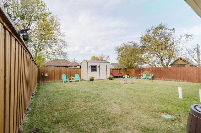 view of yard featuring a shed, a fenced backyard, a fire pit, and an outdoor structure