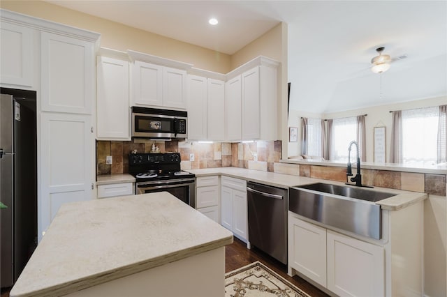 kitchen featuring a sink, a center island, appliances with stainless steel finishes, white cabinets, and decorative backsplash