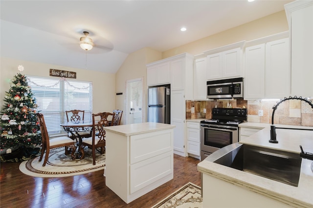 kitchen with a center island, lofted ceiling, white cabinets, tasteful backsplash, and stainless steel appliances