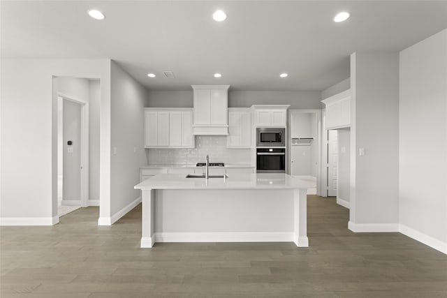 kitchen with white cabinetry, stainless steel microwave, wall oven, and sink