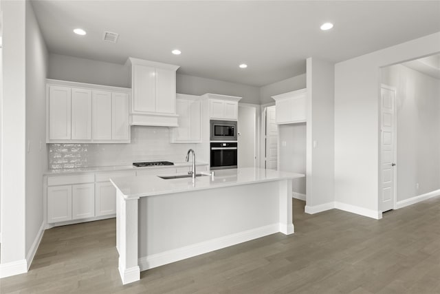 kitchen with white cabinetry, sink, black appliances, a center island with sink, and light hardwood / wood-style flooring