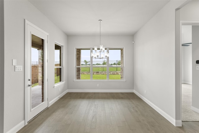 unfurnished dining area with hardwood / wood-style flooring and a chandelier