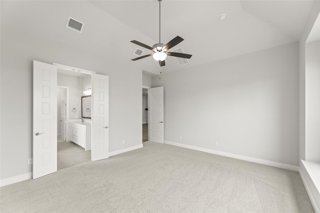 unfurnished bedroom featuring vaulted ceiling, light colored carpet, ceiling fan, and ensuite bathroom