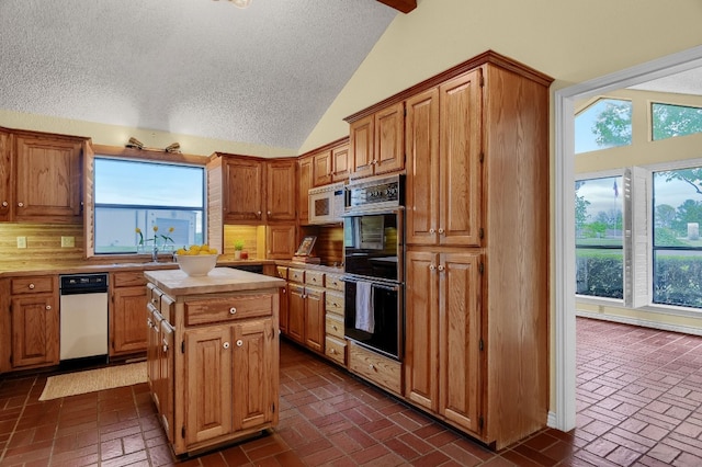 kitchen with lofted ceiling, a kitchen island, and a healthy amount of sunlight