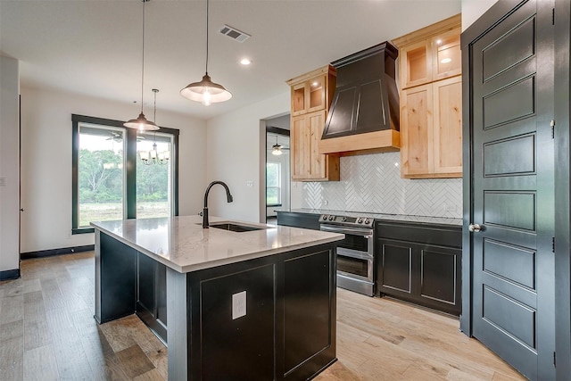 kitchen with a center island with sink, visible vents, light brown cabinets, a sink, and premium range hood