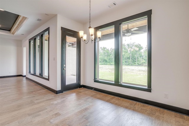 spare room with a chandelier, visible vents, light wood-style flooring, and baseboards