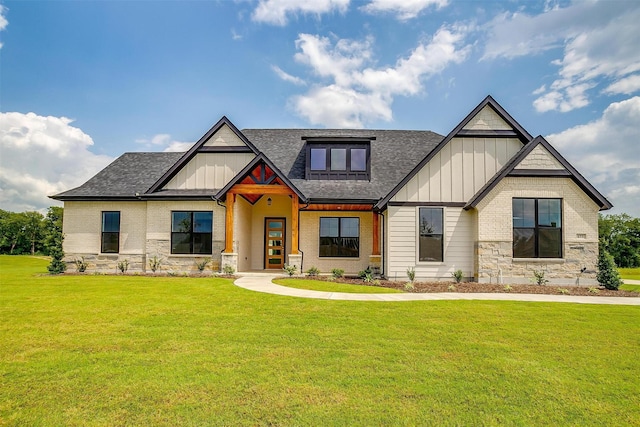 view of front of home with board and batten siding, brick siding, a shingled roof, and a front lawn