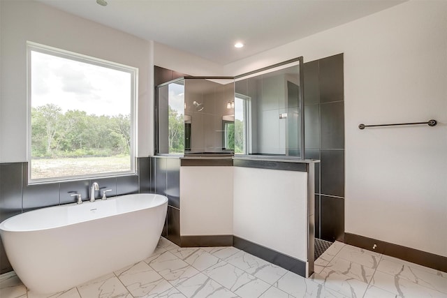 bathroom with a walk in shower, marble finish floor, a freestanding tub, and recessed lighting