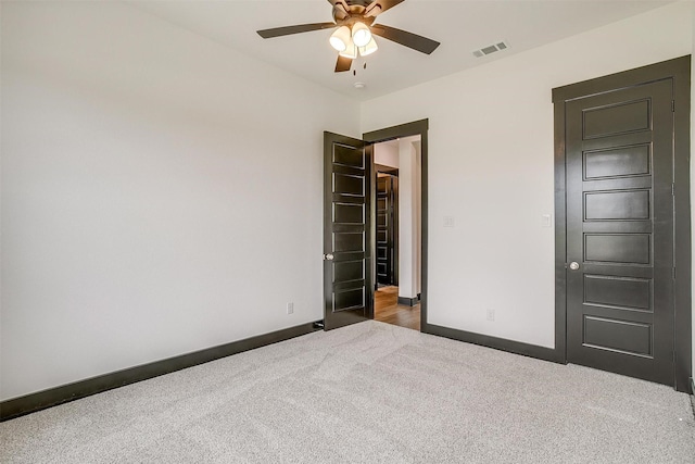 unfurnished bedroom with dark colored carpet, a ceiling fan, visible vents, and baseboards