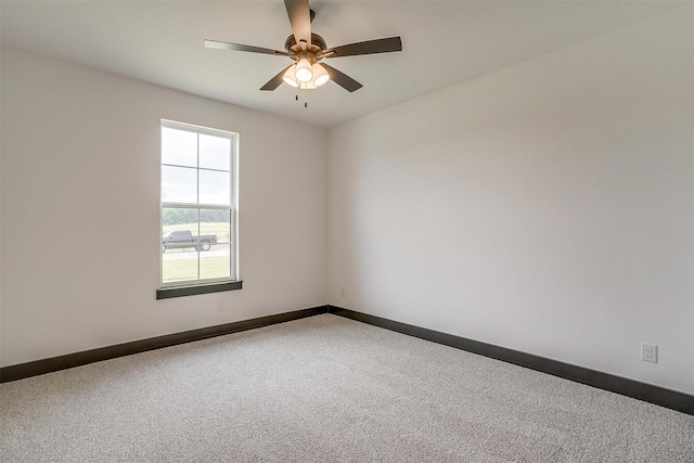 carpeted empty room with a ceiling fan and baseboards