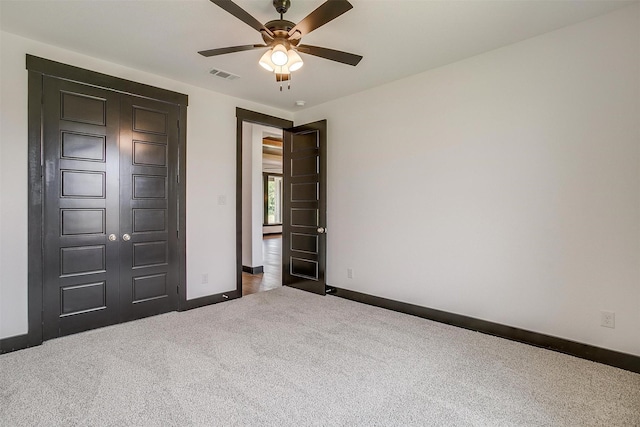 unfurnished bedroom featuring a ceiling fan, dark carpet, visible vents, and baseboards