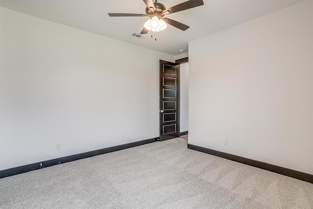 empty room with a ceiling fan, light colored carpet, visible vents, and baseboards