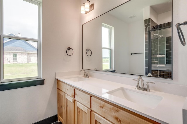 bathroom featuring a tile shower, double vanity, and a sink