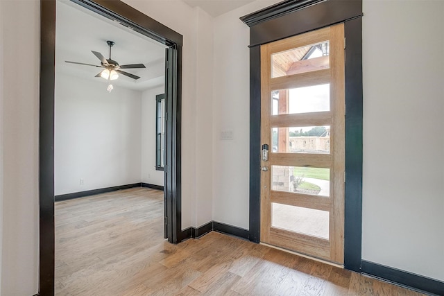 entryway featuring baseboards, a ceiling fan, and light wood-style floors