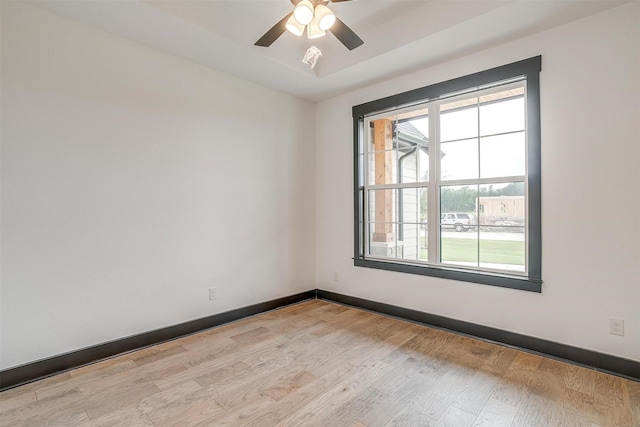 spare room with ceiling fan, light wood finished floors, and baseboards