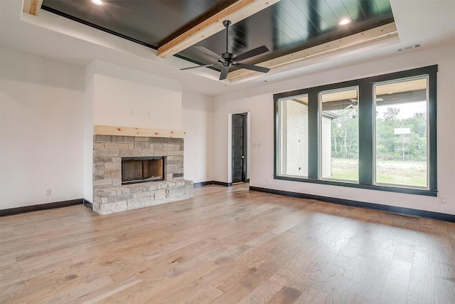 unfurnished living room with a tray ceiling, a fireplace, and light wood-style flooring