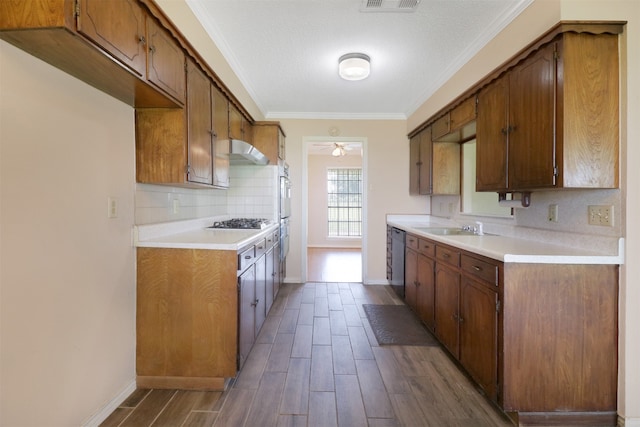 kitchen with dark wood-type flooring, ceiling fan, stainless steel appliances, ornamental molding, and decorative backsplash