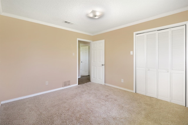 unfurnished bedroom featuring light carpet, ornamental molding, a closet, and a textured ceiling