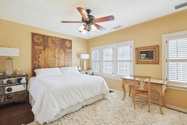 bedroom with ceiling fan, hardwood / wood-style flooring, a textured ceiling, and multiple windows