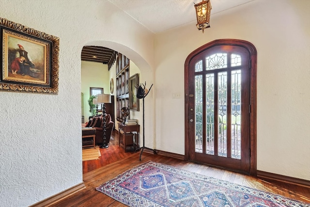 entrance foyer with vaulted ceiling, hardwood / wood-style flooring, a textured ceiling, and a healthy amount of sunlight