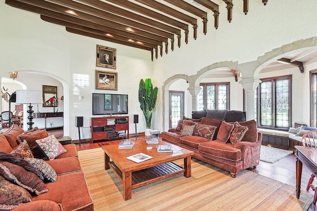 living room with beamed ceiling, light hardwood / wood-style flooring, decorative columns, and french doors