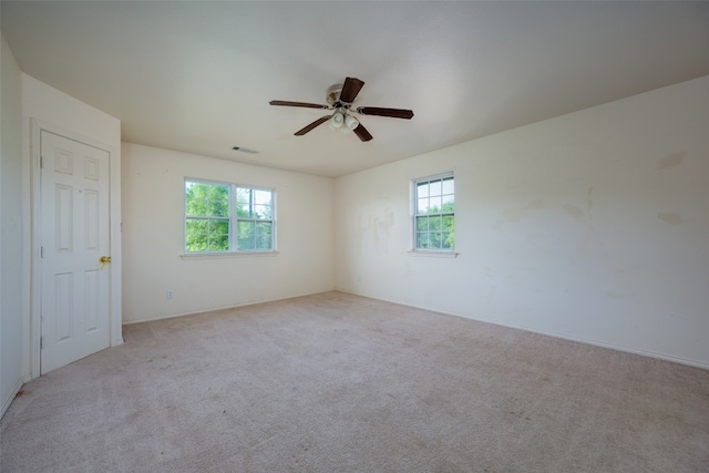 empty room with light carpet, ceiling fan, and a healthy amount of sunlight