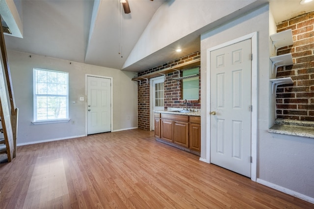 kitchen with ceiling fan, light stone countertops, sink, light hardwood / wood-style flooring, and lofted ceiling