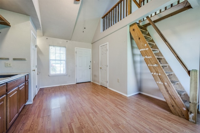 interior space with sink, high vaulted ceiling, and light hardwood / wood-style flooring