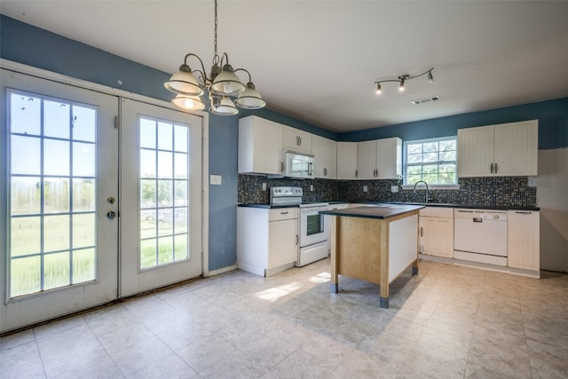 kitchen featuring hanging light fixtures, a kitchen island, a notable chandelier, white appliances, and white cabinets