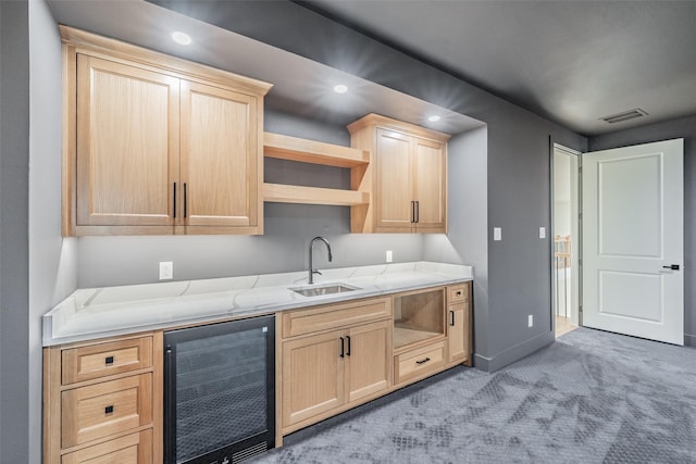 kitchen with sink, wine cooler, light stone counters, light colored carpet, and light brown cabinetry