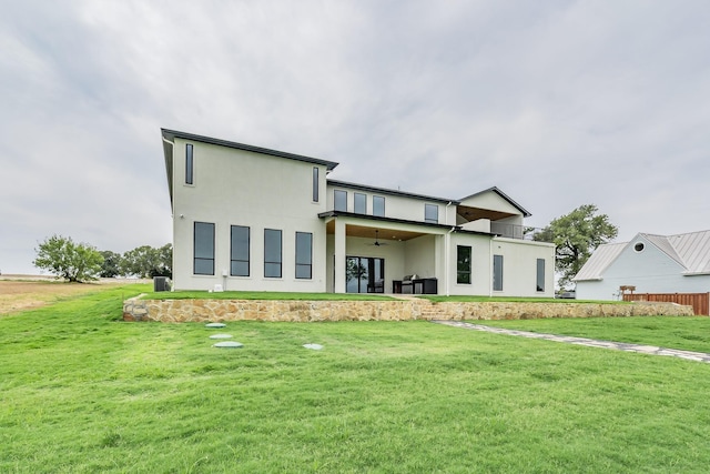 back of property with a yard and ceiling fan