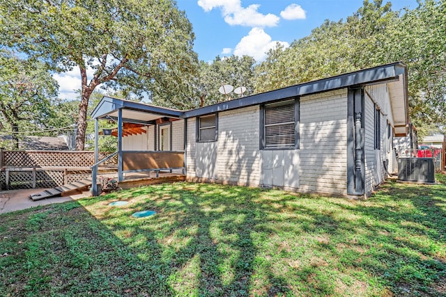 rear view of property featuring central AC and a lawn