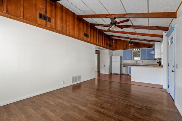 kitchen featuring kitchen peninsula, vaulted ceiling with beams, wood walls, dark hardwood / wood-style floors, and white fridge